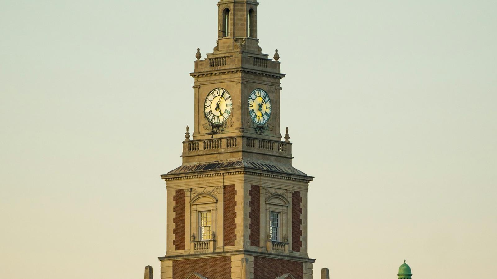 A brick clock tower against an evening sky